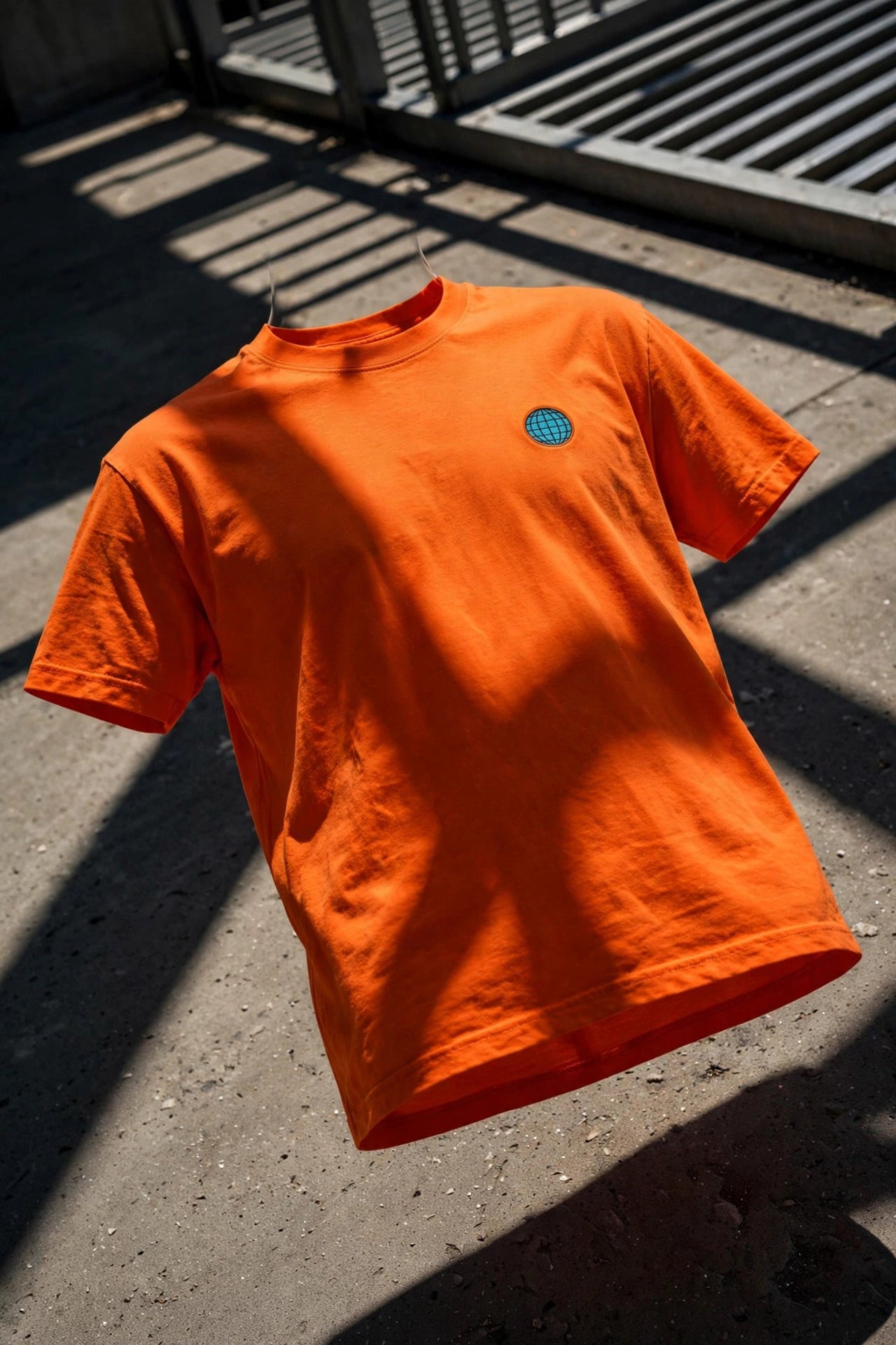 Hi-viz orange T-shirt with a small two-inch Globowrench globe logo on the left breast in harsh sunlight and dramatic hard shade