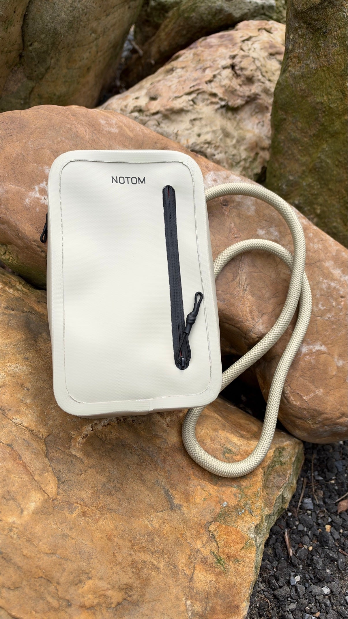 NOTOM sling bag in clay on rocks